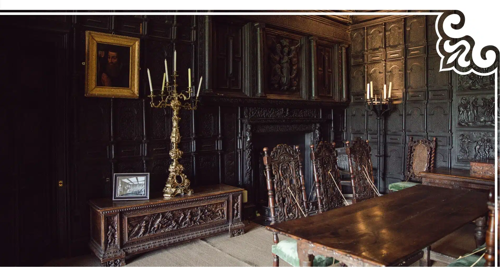 A dimly lit, ornate room reminiscent of Malahide Castle, featuring dark wood paneling and a large wooden dining table. Carved wooden chairs surround the table. A portrait hangs on the wall, and a tall, gold candelabra stands beside a wooden chest.