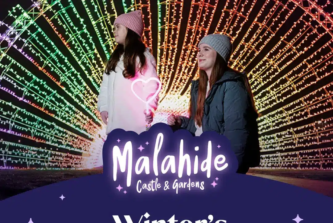 Two people in winter clothing stand before a large, colorful, illuminated arch at night. Text reads: "Wonderlights Malahide Castle & Gardens. Winter’s Brightest Tradition."