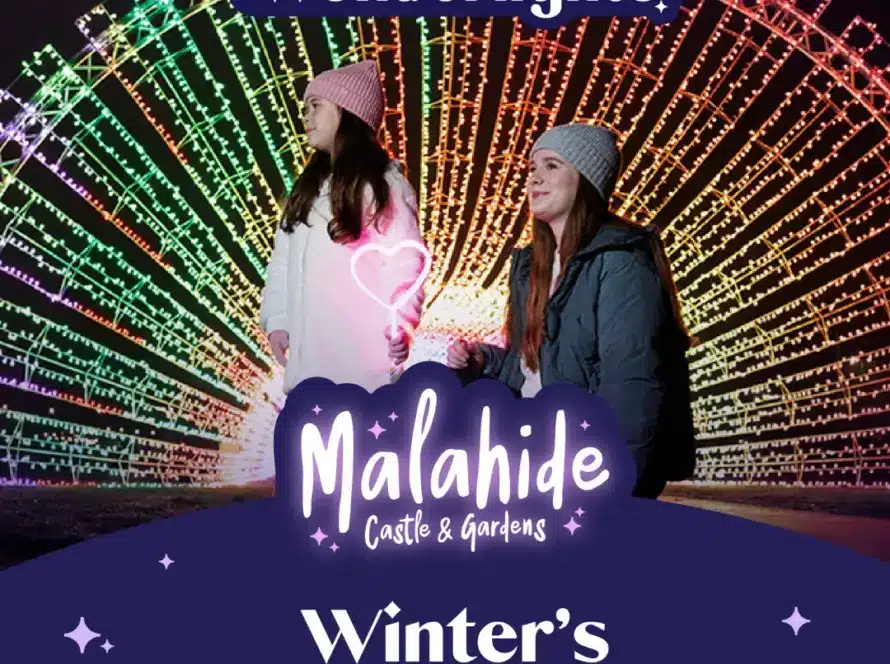 Two people in winter clothing stand before a large, colorful, illuminated arch at night. Text reads: "Wonderlights Malahide Castle & Gardens. Winter’s Brightest Tradition."