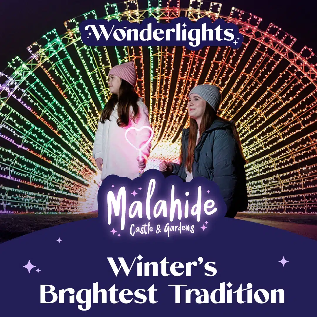 Two people in winter clothing stand before a large, colorful, illuminated arch at night. Text reads: "Wonderlights Malahide Castle & Gardens. Winter’s Brightest Tradition."
