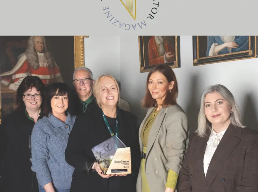 6 people standing together posing for a group photo smiling inside the castle holding an award.