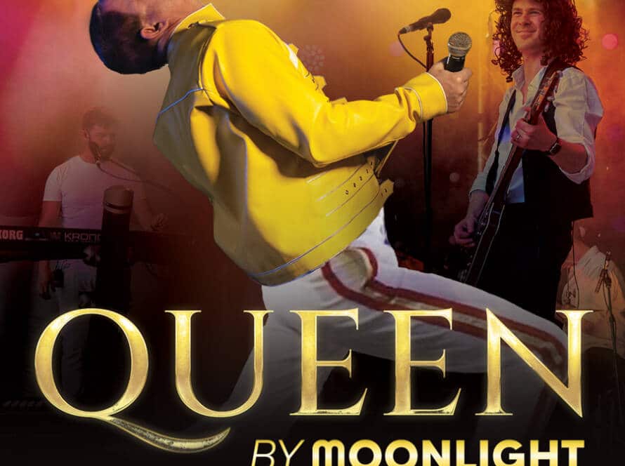 A Queen tribute band, “Queen by Moonlight,” performs onstage under colourful lights. The lead singer, dressed like Freddie Mercury, leans back with a microphone as Queen by Moonlight is written in bold letters.